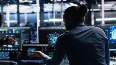 Veri merkezi sistem yöneticileri AI LLM kullanarak sinirsel ağı izlemek için PC kullanır. Asyalı adam ve iş arkadaşı sunucuların makine öğrenmesini denetlemek için yapay zeka kullanıyor. Kamera A