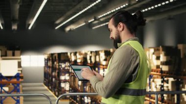 Endüstri çalışanı, dağıtım merkezindeki tablet üzerindeki havayolu faturalarını takip ederek nakliye için ekspres teslimat paketini gözden geçiriyor. Tamamlama merkezi işlemleri.