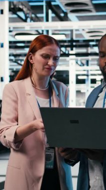 Elektroniği optimize eden dikey video sunucu çiftliğinde indüksiyon sırasında intörn öğreten dizüstü bilgisayar ve yönetici. Sistem performansı, not defteri ve veri merkezinde staj yapan takım lideri, kamera A