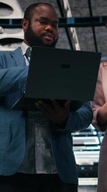 Operasyonel etkinliği arttırmak için tablet ve laptop kullanan dikey video sunucu odası takım arkadaşları. Mühendislik ekibi veri merkezinde beyin fırtınası yapıyor, dişli takozlarını izlemek için aygıtlar kullanıyor