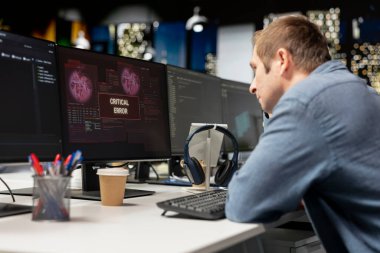 Başlangıçtaki programcı kodlama sırasında uygulama hatalarını düzeltmeye çalışıyor. Yazılım geliştirme ajansı işyerinde kodlama yaparken bilgisayar hatalarıyla uğraşan bilişim uzmanı