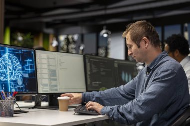 Programcı kahve içer ve yapay zeka otomasyonunu kullanarak programlar geliştirmek için teknoloji şirketinde derin öğrenim kullanır. İşçi sinirsel ağ teknolojisiyle uygulamaları düzeltirken içecekten keyif alıyor