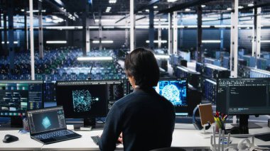 Veri Merkezi Sistem Yöneticisi AI sistemlerini kontrol ediyor. Zaman ve verimlilik için. Sunucu merkezindeki bilgisayar ve dizüstü bilgisayarda yapay zeka teknolojisi kullanan IT çalışanı, kamera A