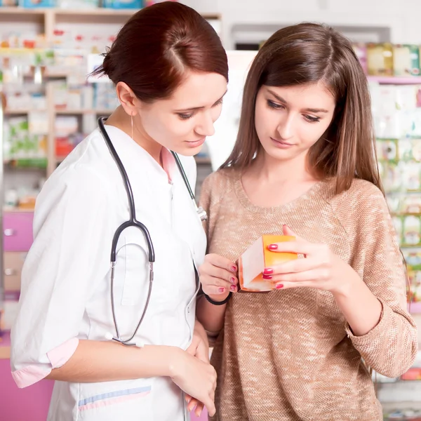 Farmacéutico y cliente mirando la caja de medicamentos — Foto de Stock