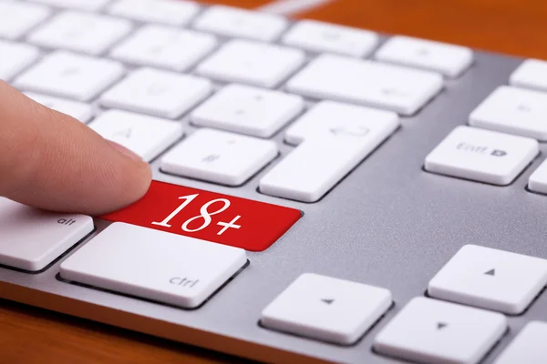 Finger drücken auf roten Knopf mit 18 + drauf — Stockfoto