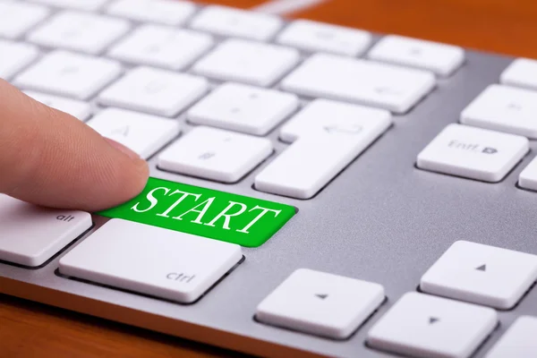 Finger pressing green start button on keyboard — Stock Photo, Image