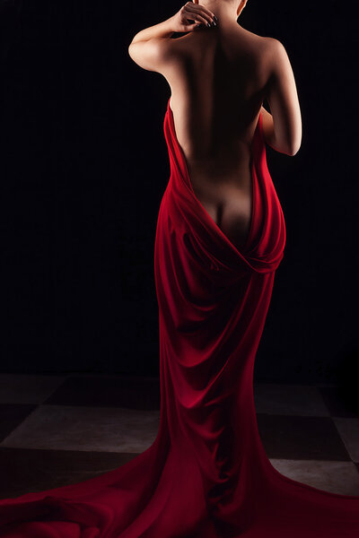 Artistic nude back of woman with red drapes around her. Studio shooting. Beauty and sexy artistic nude