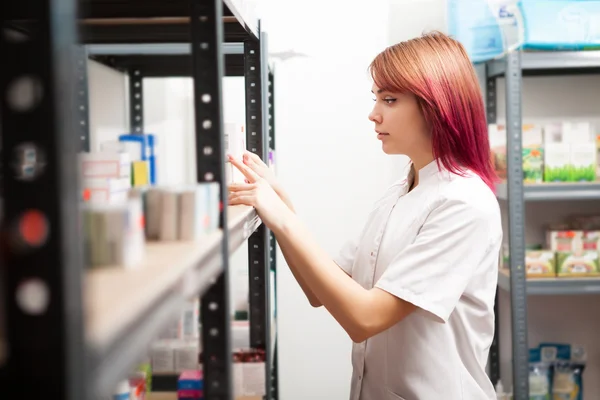Mujer farmacéutica inspeccionando productos en almacén — Foto de Stock