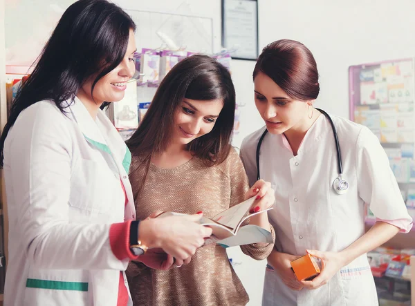 Two doctors showing products in catalog to client — Stock Photo, Image