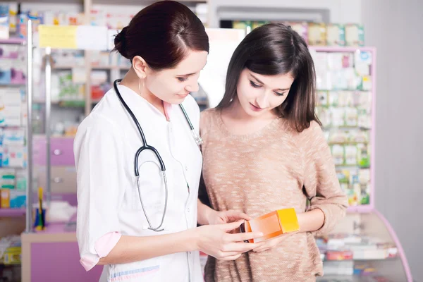 Doctor woman in uniform showing product to customer — Stock Photo, Image