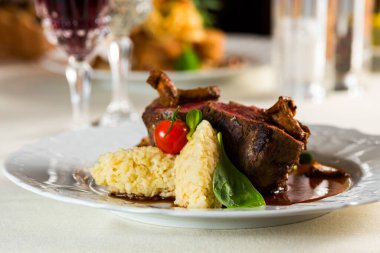 Güzel kızarmış biftek, yulaf lapası, domates mantarı ve fesleğenle süslenmiş.