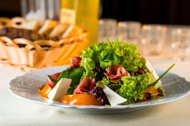 Jamon, sebze ve sebze salatasıyla bir tabakta peynir.