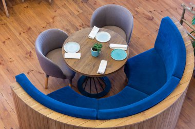 Masanın etrafındaki koltuklar ve kanepeler ahşap zemin üzerinde, yakın çekim üst manzara