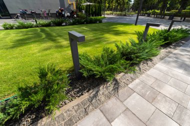 Sokak lambası ardıç ağacının yanında ve kiremitler kaldırımda çimenlikte peyzaj evin avlusunda