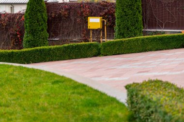 Dekoratif manzara ağaçları ve granit bir yol boyunca uzanan çalılarla dolu özel bir arazinin peyzajı.