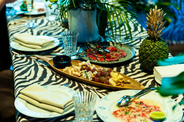 set of sliced cheese and meat with grapes on a served banquet table