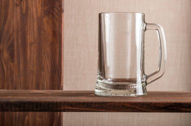 Tahta bir masanın üstünde boş bir bardak bira.