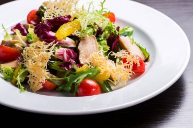 Taze sebze salatası ve füme kümes hayvanı. Izgara peynir ve portakal dilimiyle süslenmiş.