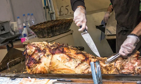 Niezidentyfikowany szef kuchni cuting pieczone świnia na małym rynku na południowym brzegu Tamizy. Londyn, Wielka Brytania — Zdjęcie stockowe