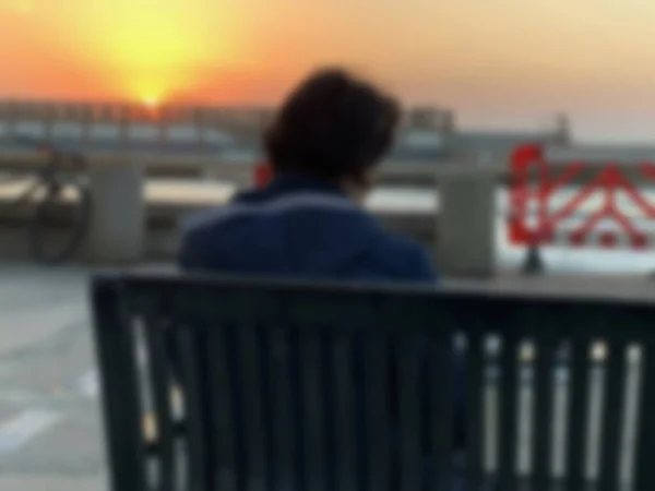 若い孤独な女性のシルエットは 海の背景の上に明るい日没のベンチに座っている ぼやけた景色 — ストック写真