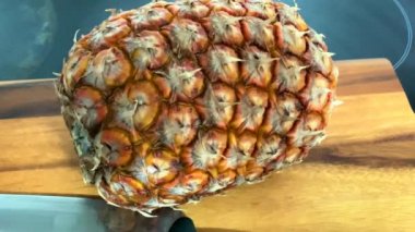 Tahta kesme tahtasında ananas meyvesi ve büyük bir mutfak bıçağı. 4K