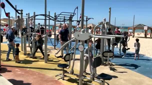 特拉维夫 以色列 2019年3月9日 在地中海戈登海滩 Mediterranean Gordon Beach 不明身份的男子带着孩子在户外运动装备上运动 运动员在公共场所使用模拟器 — 图库视频影像