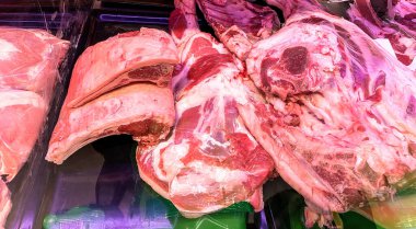 Süpermarkette tezgahın üzerinde duran camların arkasında büyük taze domuz parçaları var.