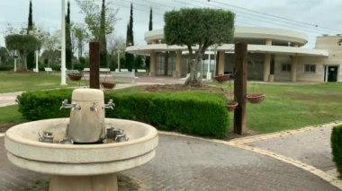 Nahariya, İsrail - 15 Nisan 2019: Mezarlığı ve arka plandaki ayin odasını ziyaret ettikten sonra Yahudi geleneklerine göre ellerini yıkamak için bir su kaynağı. 4K