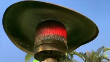 Koyu mavi gökyüzü arka planında paslanmaz çelik, açık hava restoranı gaz teras ısıtıcısı tasarla. Yakıcı ve alevler. 4K