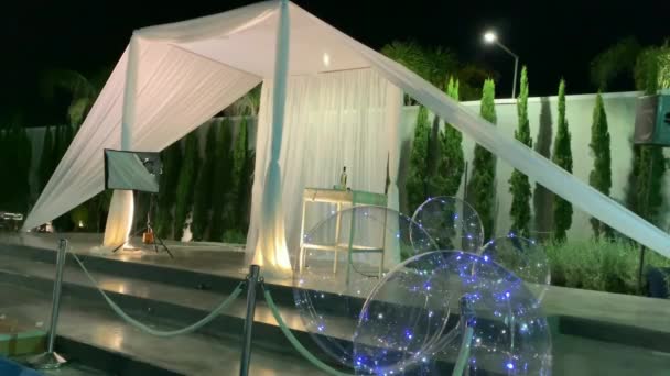 犹太传统婚礼户外仪式 Chuppah Hupa 由白色面料制成 背景为夜空 棕榈和装饰有气球的人造水库 — 图库视频影像