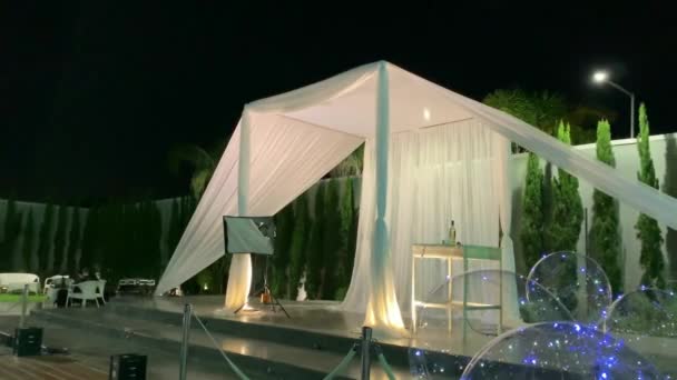 ユダヤ教の伝統結婚式屋外式 夜空を背景に白い布で作られた結婚式の礼拝堂 手のひらと風船で飾られた人工貯水池 — ストック動画