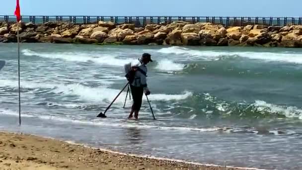 テルアビブ イスラエル 2021年5月5日 金属探知機を持つ男は ビーチや砂の底の水の下でいくつかの失われたお金のコインや金の宝石の宝物を探しています — ストック動画