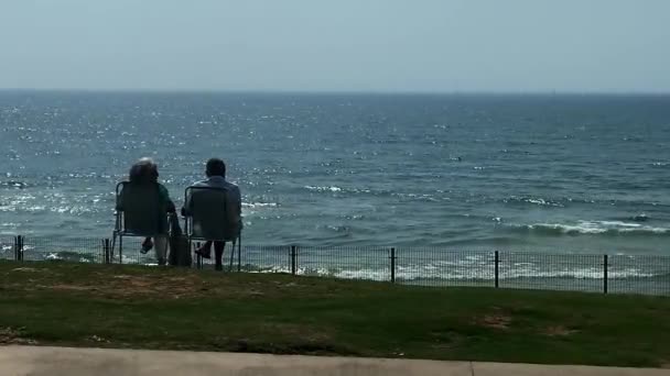 特拉维夫 以色列 2021年4月15日 老年男女在略带狂风暴雨的大海背景下坐在折叠椅上休息 — 图库视频影像