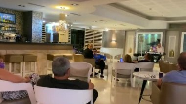 Ölü deniz, İsrail - 7 Mayıs 2021: Otel lobisinde akşam dinlenmesi. Otel konukları müzisyenin performansını dinliyor. HD