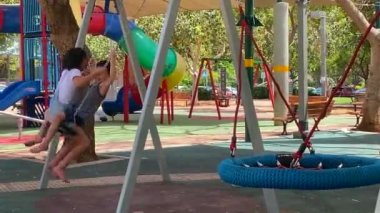 Tel Aviv, İsrail - 12 Mayıs 2021: Rahat küçük oğlan ve kız çocuk parkında salıncakta sallanıyor. Arkadaşlık ve rahatlık kavramı. HD