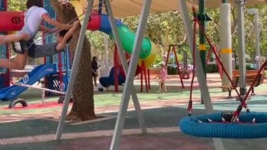 Tel Aviv, İsrail - 12 Mayıs 2021: Rahat küçük oğlan ve kız çocuk parkında salıncakta sallanıyor. Arkadaşlık ve rahatlık kavramı. HD