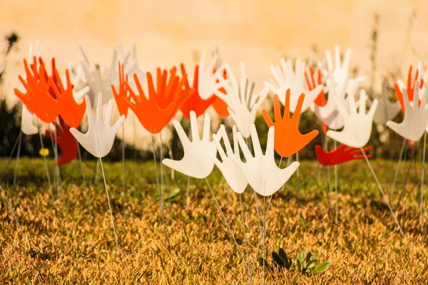 Muitos acenando abstrato mãos sinais ou bandeiras instalados em um gramado gramado — Fotografia de Stock