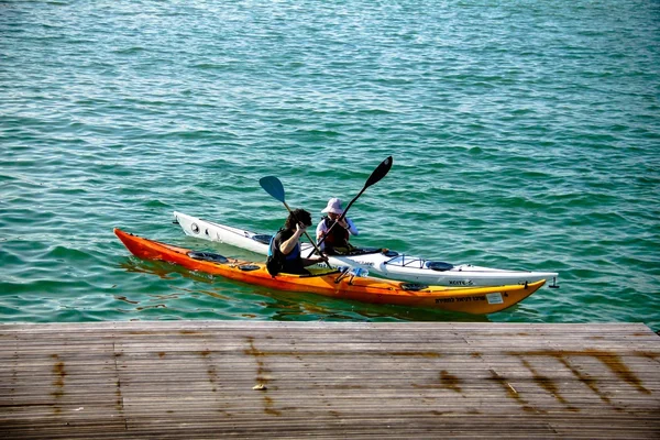 Orange and white kayaks with rowers near berth — Stok fotoğraf