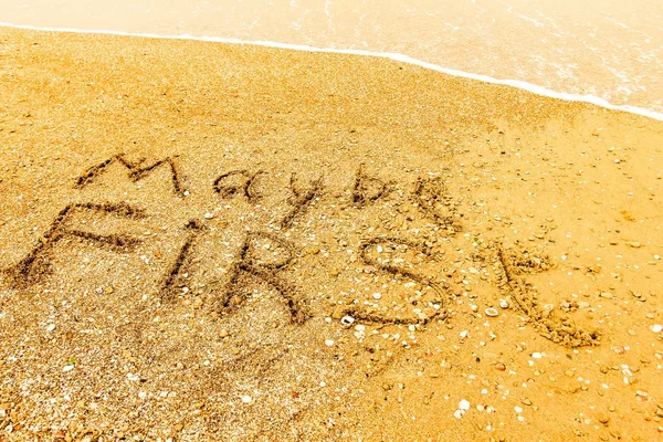 The word MAYBE FIRST written on a sandy beach in bold. — Stock Photo, Image