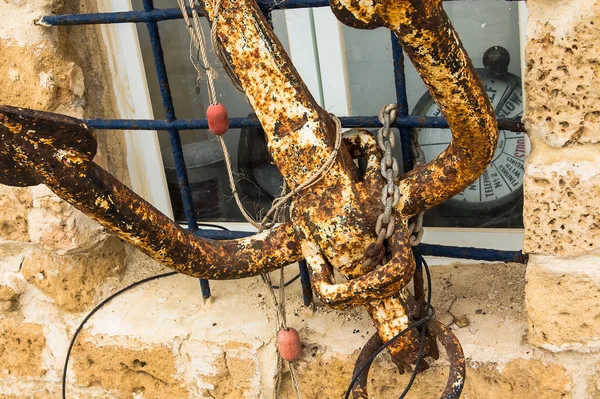 Der alte Metallanker, der an den Gittern am Fenster des Gebäudes befestigt ist — Stockfoto