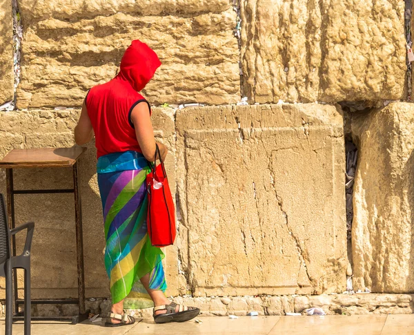 Niet-geïdentificeerde toerist in een heldere rode jas en kleurrijke vrouwelijke sjaal, herbergen benen in korte broek op de westelijke muur — Stockfoto