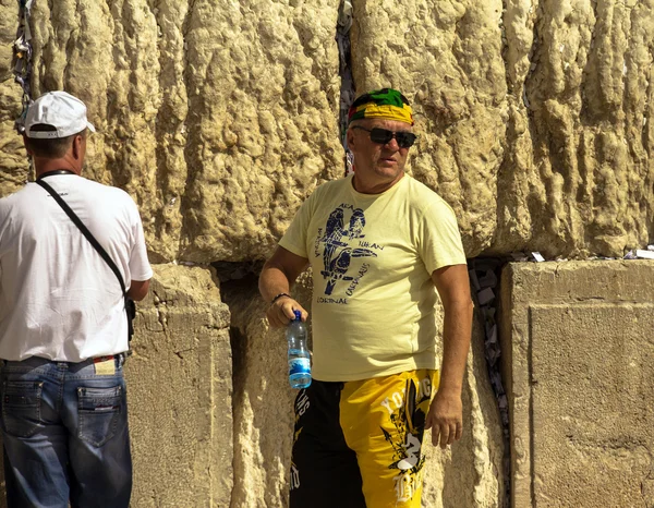 Turista desconocido en pantalones cortos amarillos y un pañuelo de colores brillantes en su cabeza en el Muro Occidental —  Fotos de Stock