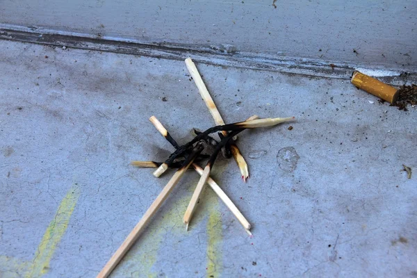 Burnt and burning matches  and a cigarette butt on windowsill — Stock Photo, Image
