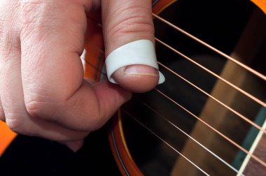 Detail of a guitar player hand using a thumbpick to play fingerstyle and fingerpick music clipart
