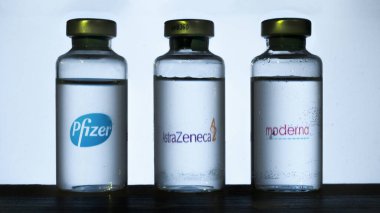 Carrara, İtalya - 05 Şubat 2021 - Arka planda bulanık Pfizer, Astrazeneca ve Moderna logolarına sahip covid-19 aşısı şişeleri bulanıklaştı