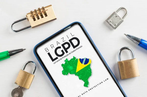 LGPD (Brezilya veri koruma yasası) kavramı: asma kilitlerle çevrili akıllı telefon ve Brezilya veri koruma yasasını okumak için bir bağlantı gösteren hayali bir sayfa (Lei Geral de Protecao de Dados Pessoais)