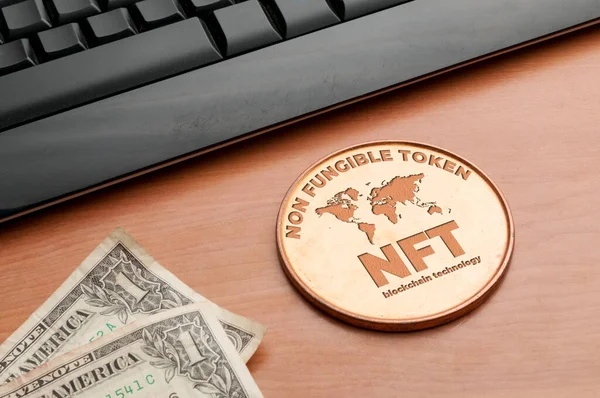 Nft (ödenebilir olmayan jeton) kavramı: bir bilgisayar klavyesi ve iki dolarlık banknotları olan ahşap bir masanın üzerindeki büyük bakır para