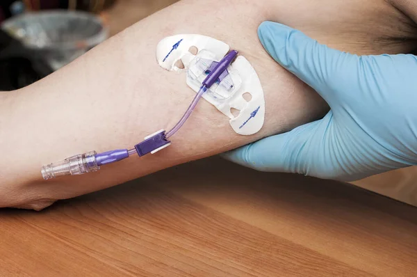 Doktor, göğüs kanseri için kemoterapi gören bir kadının kolundaki PICC hattını kontrol ediyor.