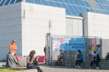 Carrara, İtalya - 3 Haziran 2021 - İtalya 'nın Toskana kentindeki toplu aşılama merkezlerinden birinin girişinde aşı bekleyen insanlar.