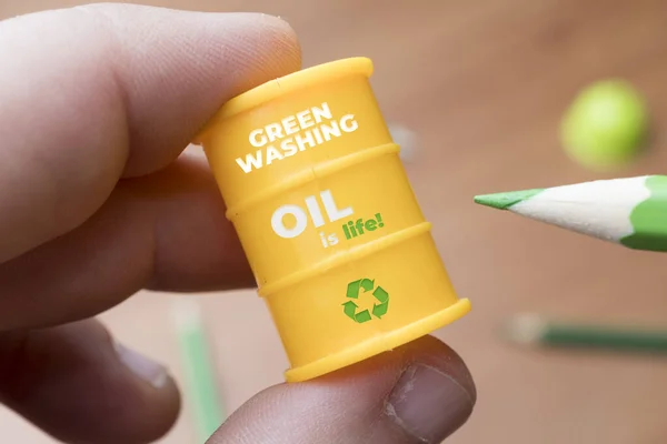 緑洗浄の概念 男は緑色の鉛筆で油の樽を描く Greenwashingは 環境面で企業の誤ったイメージを構築することを目的とした通信技術です — ストック写真